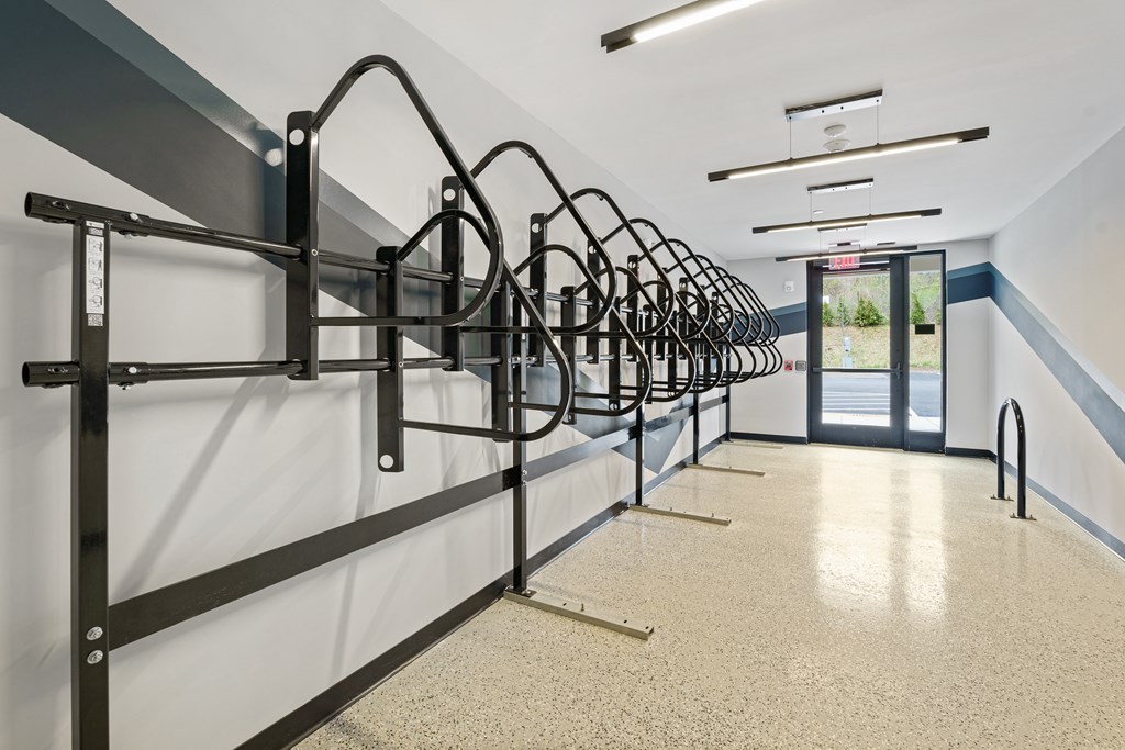 A row of black bike racks are lined up against a wall.