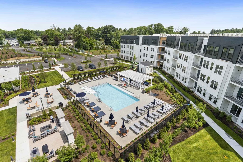 A large swimming pool surrounded by lounge chairs and umbrellas is the centerpiece of a resort-style outdoor area.