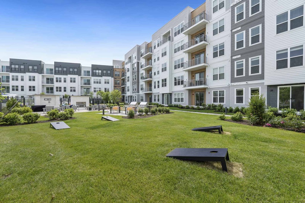 A grassy area with benches in front of apartment buildings.