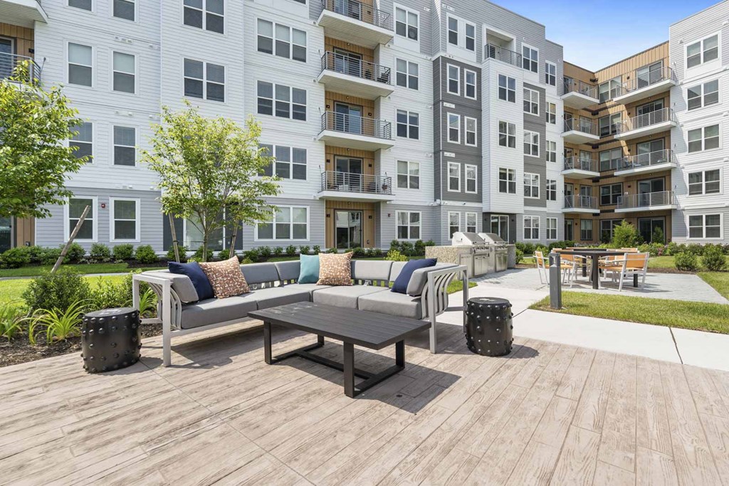 A wooden table is surrounded by chairs and a bench on a wooden deck.