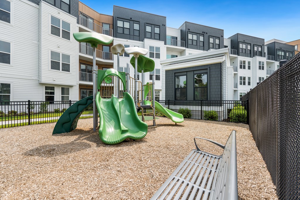 A playground with a green slide and a metal slide.