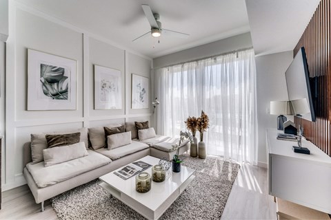 A modern living room with a white sofa, coffee table, and a ceiling fan.