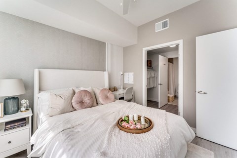 A bedroom with a large bed and a tray of fruit on the pillow.