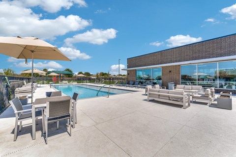 A poolside area with chairs and an umbrella.