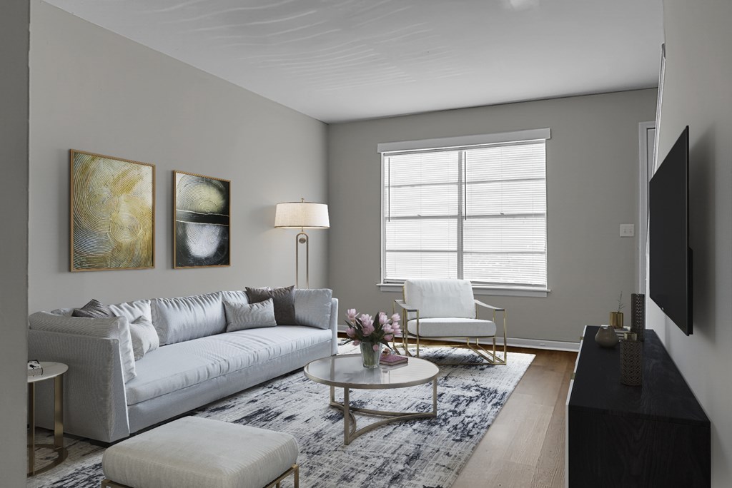A living room with a grey couch, a white chair, a coffee table, and a flat screen TV.