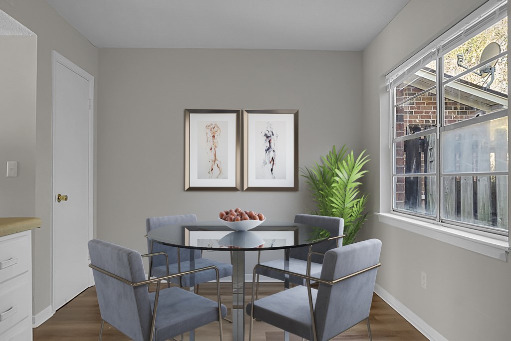 A dining room with a glass table and grey chairs.