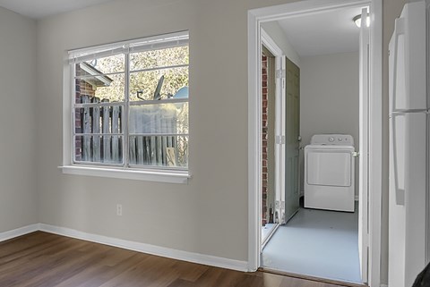 A white refrigerator is in a kitchen next to a window.