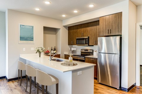 A kitchen with a white counter top and a stainless steel refrigerator.