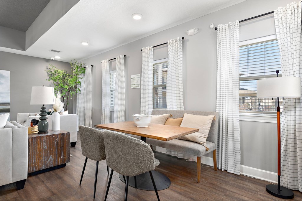 A modern living room with a wooden table and grey chairs.