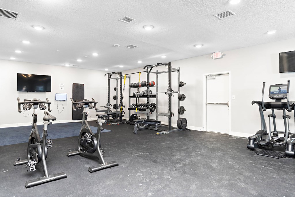 A gym with a variety of exercise equipment including stationary bikes, weightlifting machines, and a treadmill.