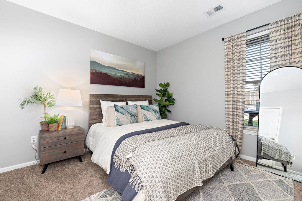 A bedroom with a large bed and a painting on the wall.