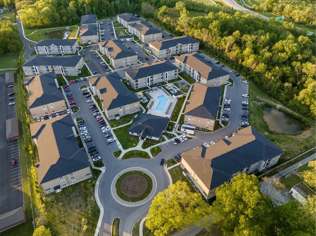 An aerial view of a residential complex with a swimming pool and surrounded by trees.