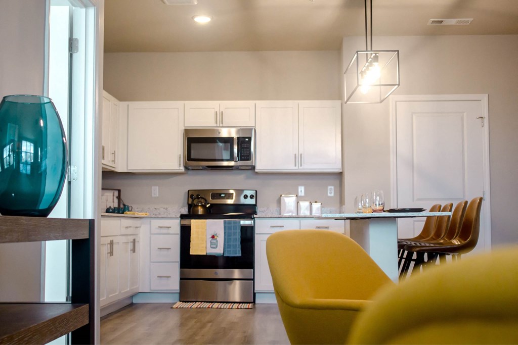 A modern kitchen with a yellow chair in the foreground.