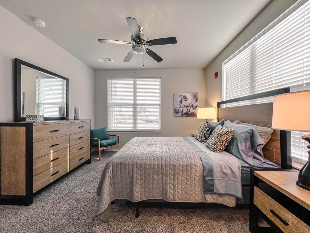 A bedroom with a bed, dresser, and window.