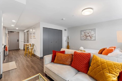 A living room with a white couch and orange pillows.
