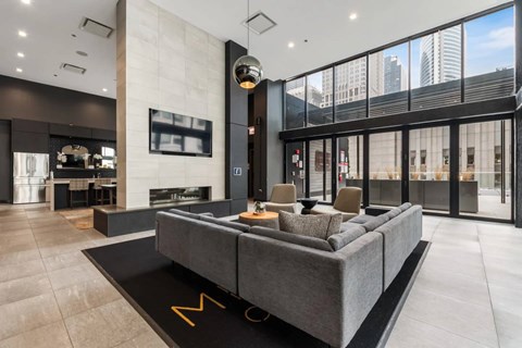 A modern living room with a grey sofa and a large window overlooking the city.
