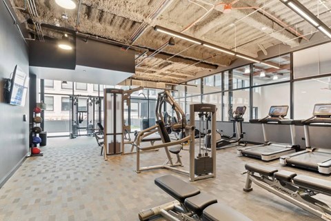 A gym with a variety of equipment including treadmills, weights, and exercise machines.