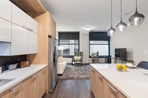 A modern kitchen with a refrigerator, sink, and a dining area with chairs and a table.