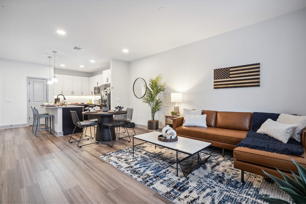 A modern living room with a dining area and a kitchen in the background.