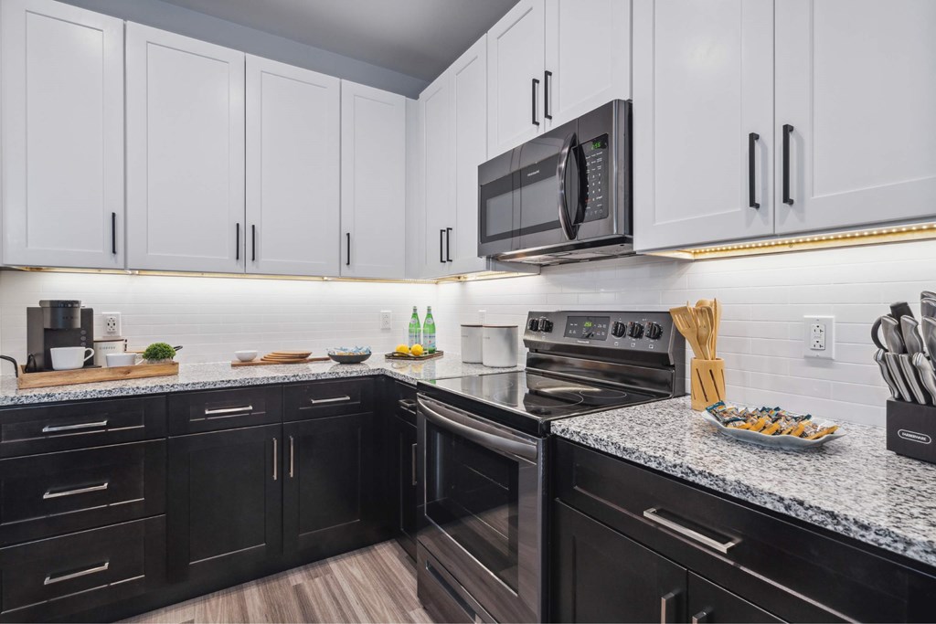 A kitchen with black and white cabinets and appliances.