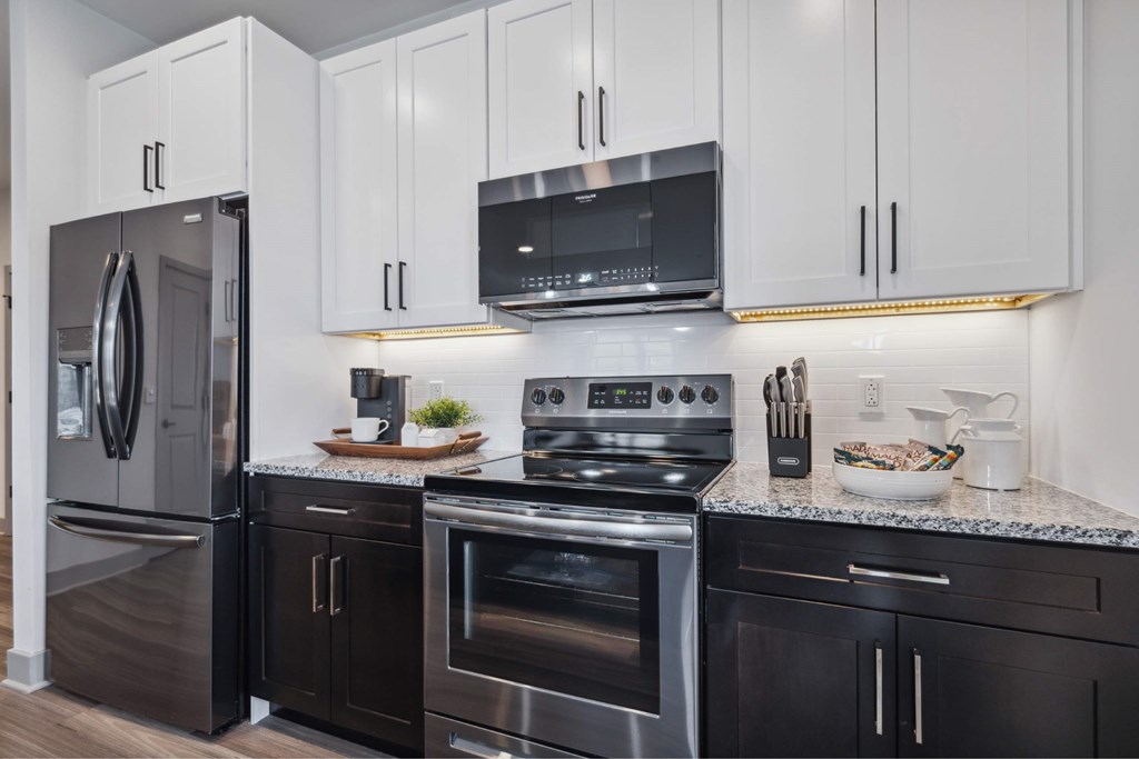 A modern kitchen with a stainless steel refrigerator, oven, and microwave.