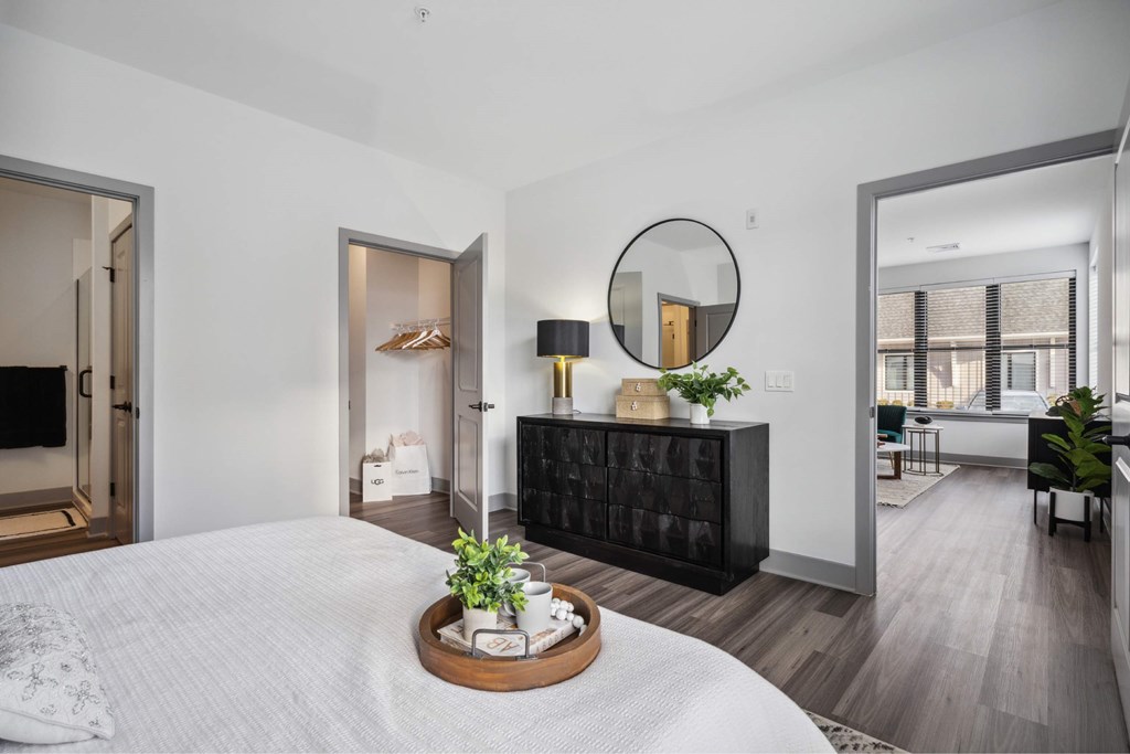 A modern bedroom with a large bed and a round mirror on the wall.
