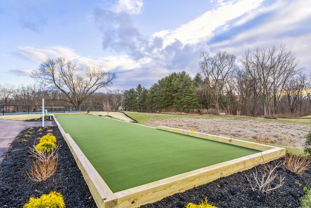 A miniature golf course with a green surface and yellow flowers on the side.