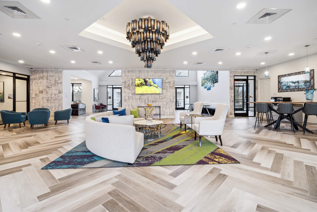 A spacious living room with a white sofa set and a chandelier.