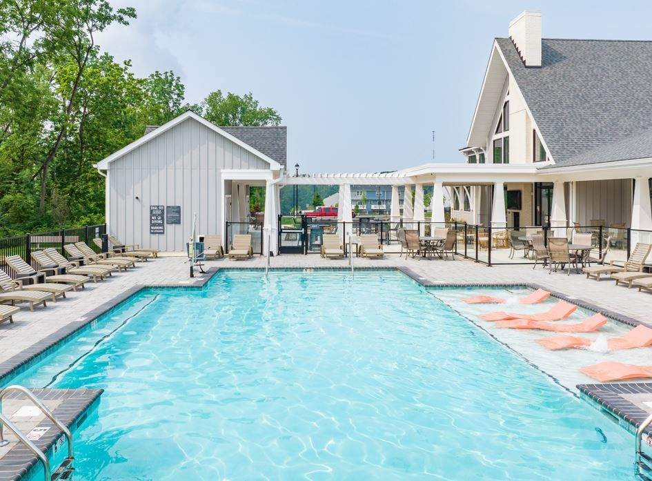 A large swimming pool with lounge chairs and a building in the background.