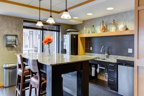 A kitchen with a marble countertop and a dining table with chairs.