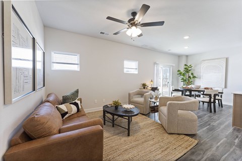 A living room with a brown couch and a ceiling fan.