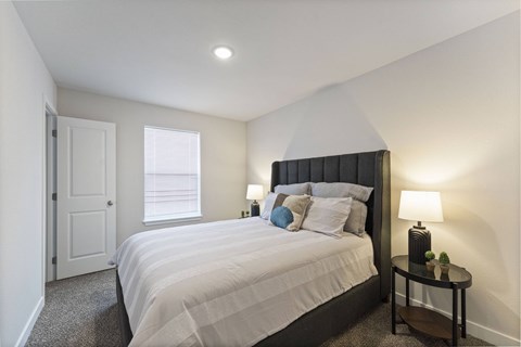 Kansas City, MO, Pet-Friendly Villas - Barry West - Bedroom With Upholstered Bed, White Bedding, Nightstands With Lamps, Neutral Walls, And A Window.