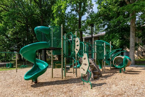 A playground with a green slide and climbing structures.