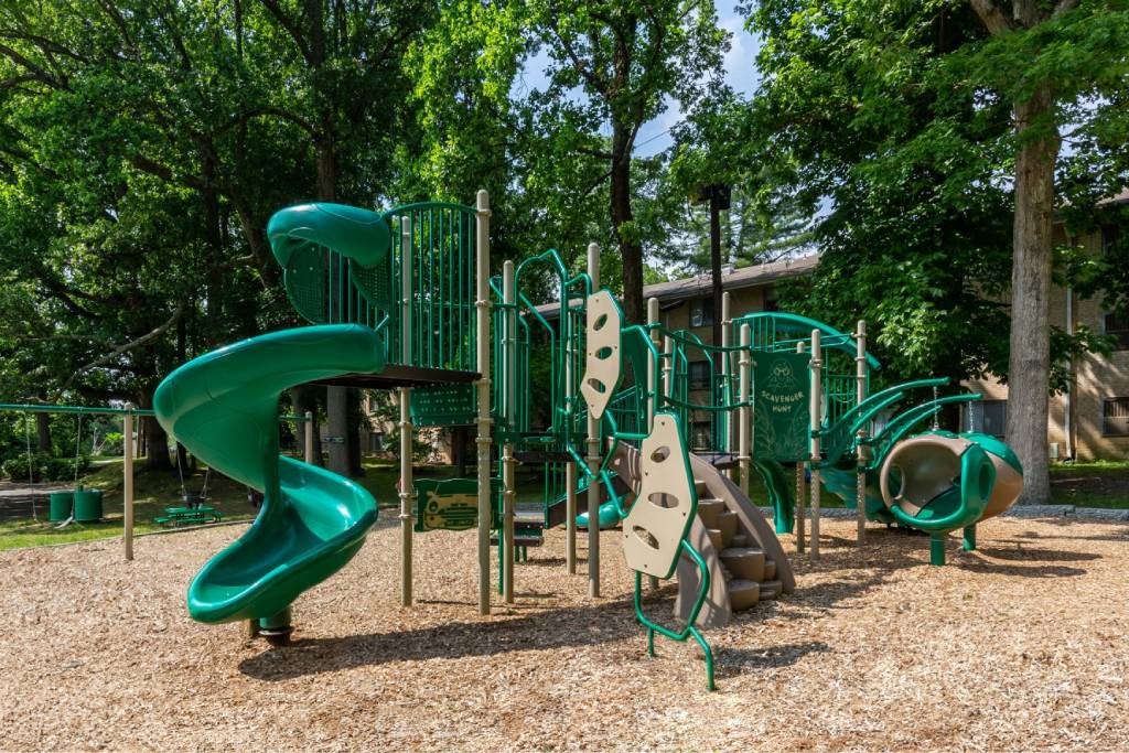 A playground with a green slide and climbing structures.