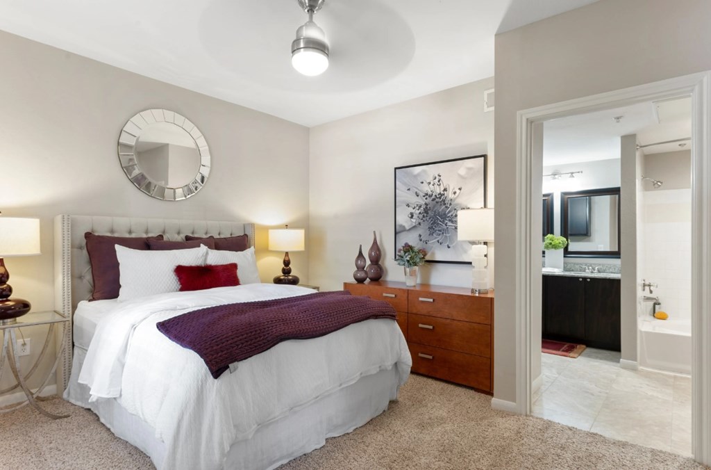 A bedroom with a white bed and a round mirror on the wall.