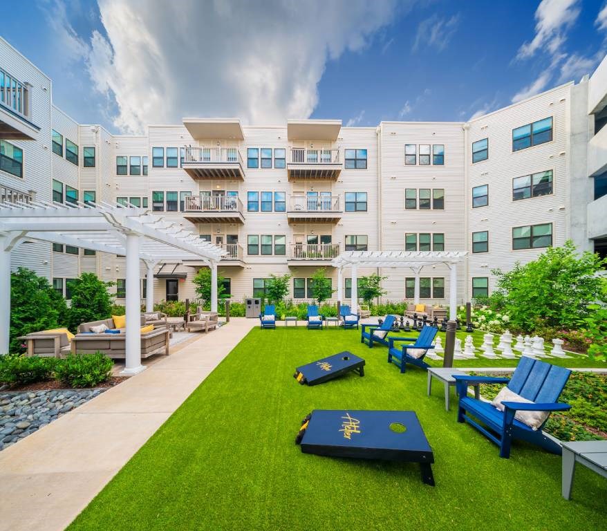 A white building with blue chairs and tables in front.