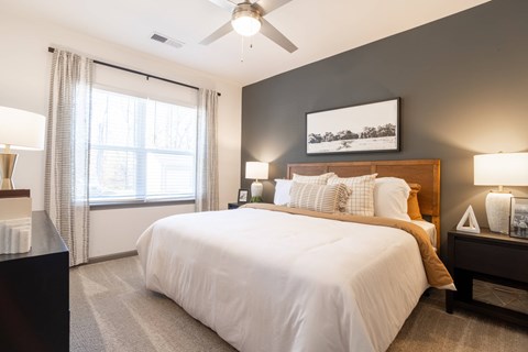 A bedroom with a large bed and a ceiling fan.