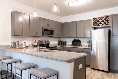 A kitchen with a stainless steel refrigerator and grey cabinets.