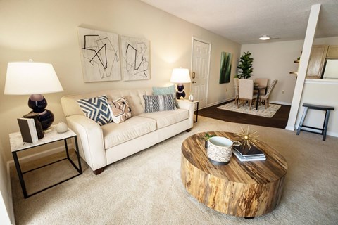 A living room with a white couch and a wooden coffee table.