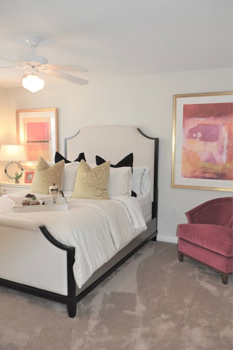 A bedroom with a white bed and a pink chair.