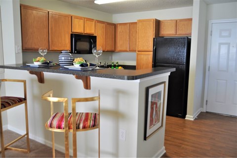 A kitchen with a black refrigerator and wooden cabinets.