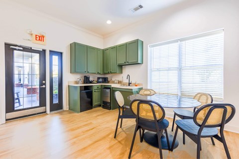 A kitchen with green cabinets and a dining table with chairs.
