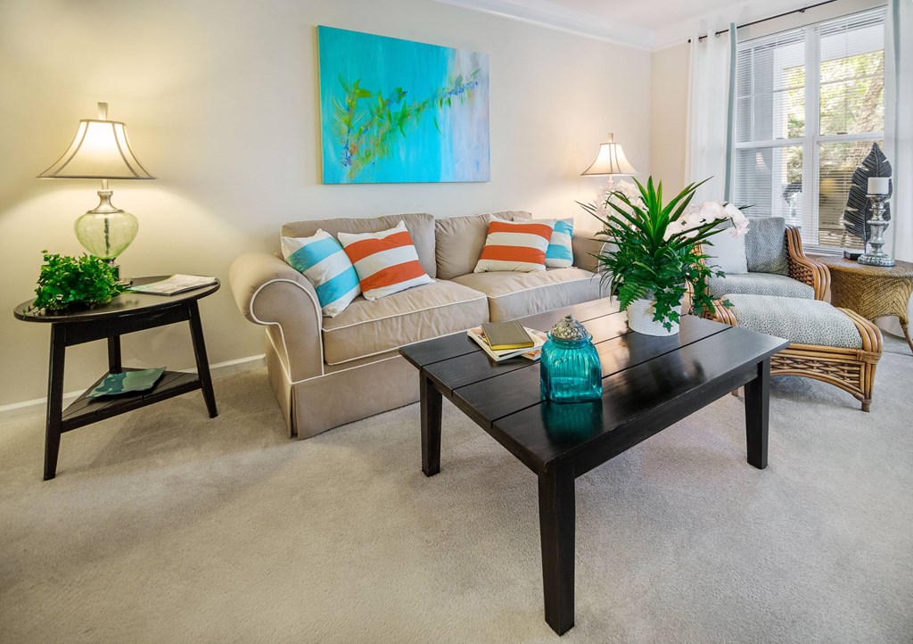 A living room with a couch, a chair, a table, and a painting on the wall.