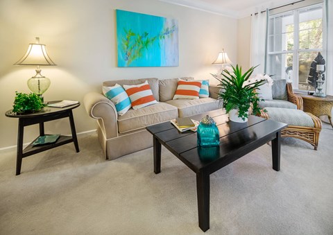 A living room with a couch, a chair, a table, and a painting on the wall.