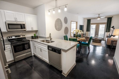 A kitchen with white cabinets and black countertops.