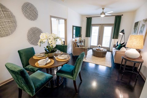 A dining room with a table set for two and green chairs.