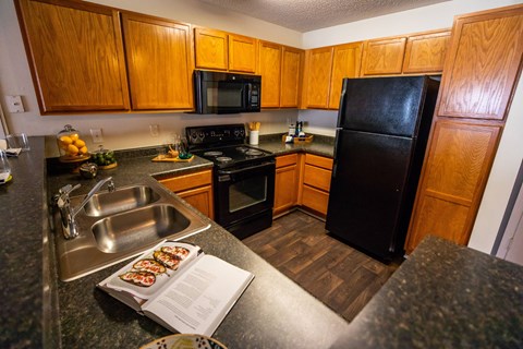 A kitchen with wooden cabinets and a black refrigerator.