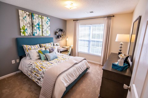 A bedroom with a large bed and a window with curtains.