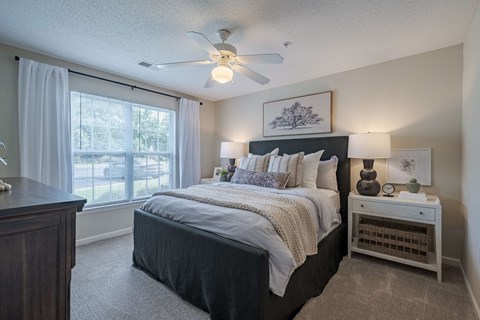 A bedroom with a large bed and a ceiling fan.