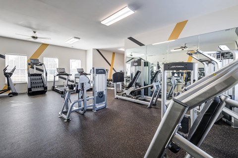 A gym with a variety of equipment including treadmills, weights, and exercise machines.